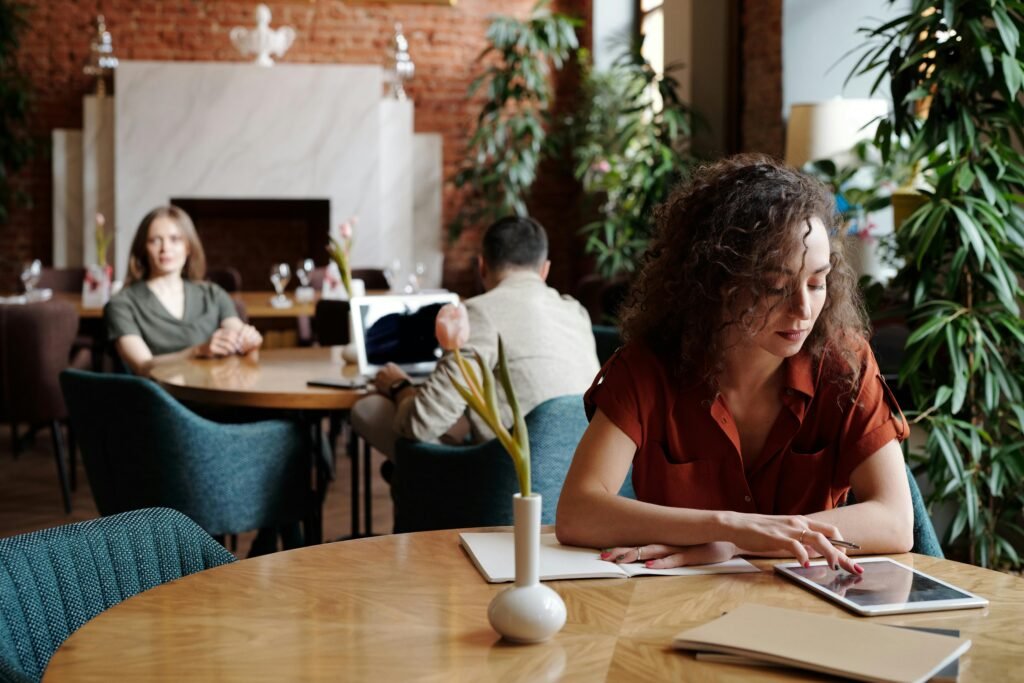 Woman engaged in remote work on tablet in a stylish cafe setting.